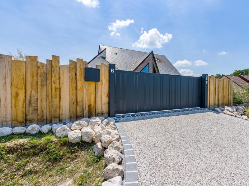 Portail coulissant anthracite et clôture en bois devant une maison contemporaine