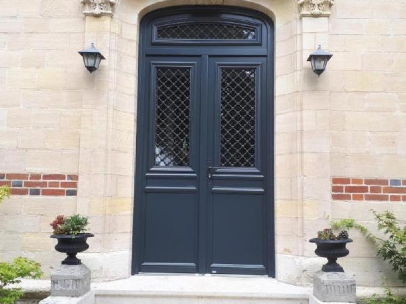Double porte d'entrée anthracite à grilles décoratives sous arche en pierre