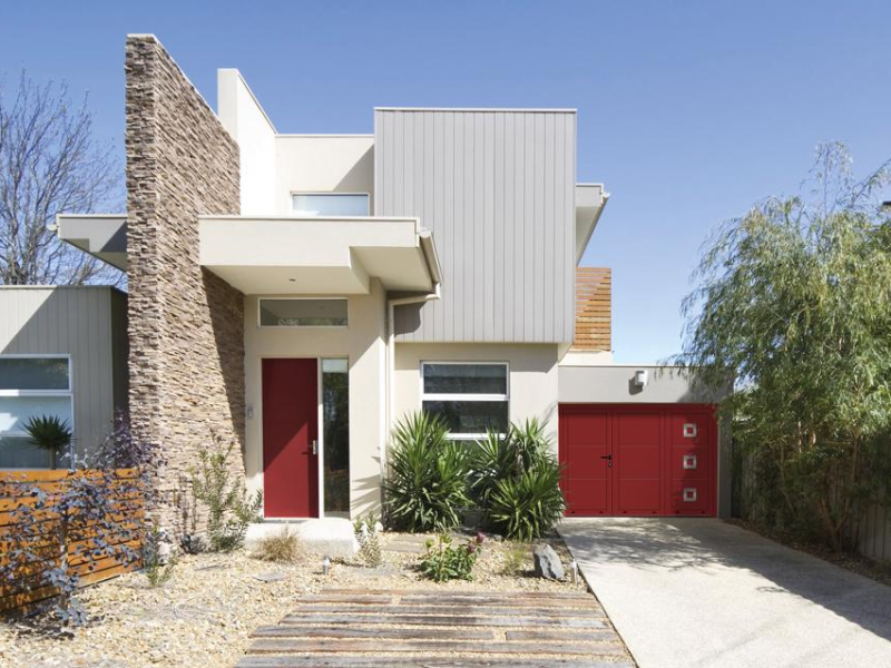 Maison moderne avec porte de garage double rouge à hublots et porte d'entrée assortie