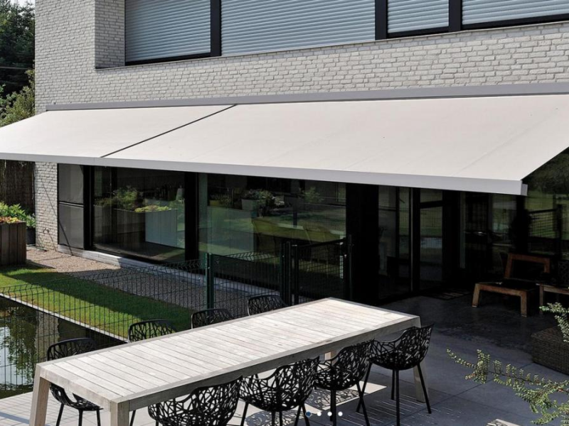 Store banne tendu au-dessus d'une terrasse avec table et chaises