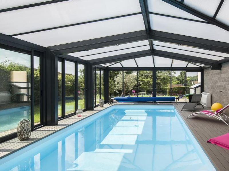 Abri de piscine aluminium anthracite et toiture translucide, bassin et deck gris