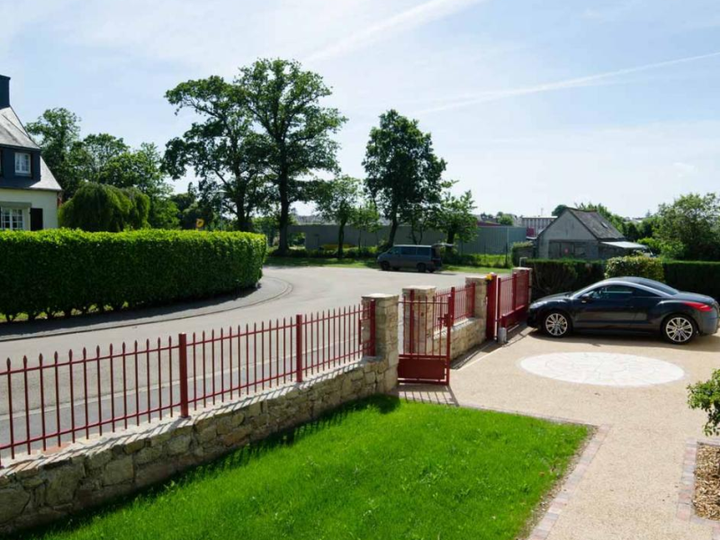 Clôture et portail rouge bordeaux à barreaux pointus sur muret en pierre