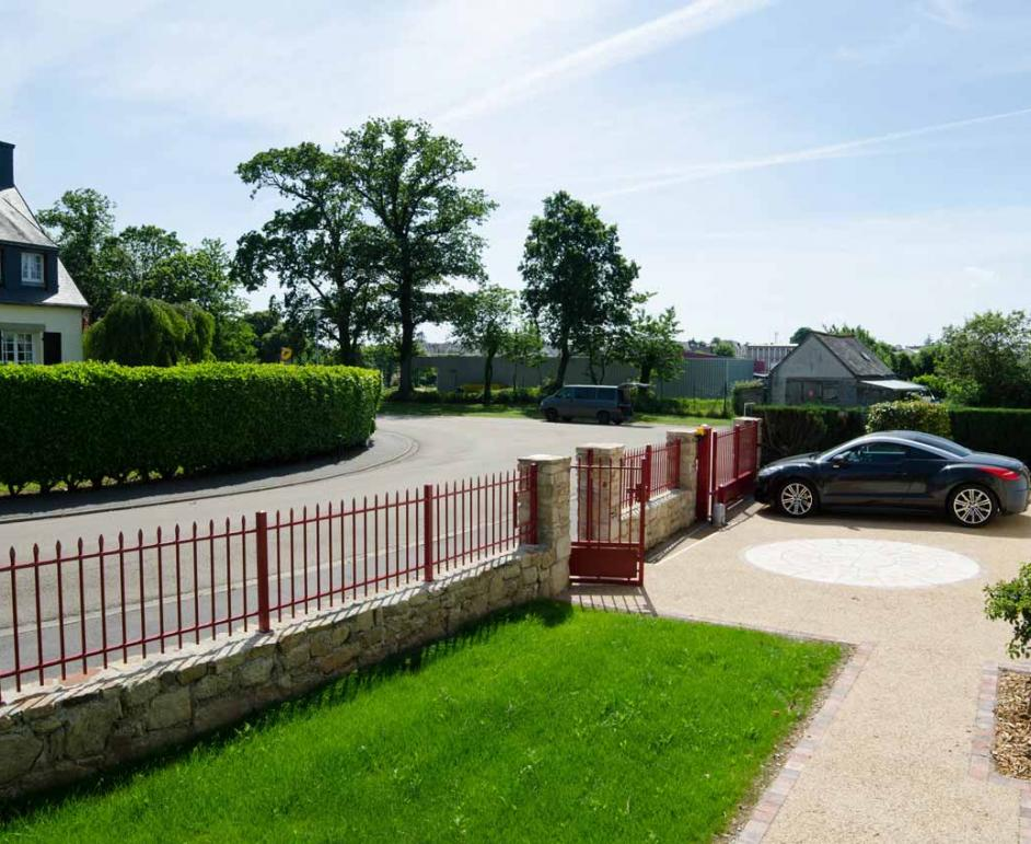 Clôture et portail rouge bordeaux à barreaux pointus sur muret en pierre