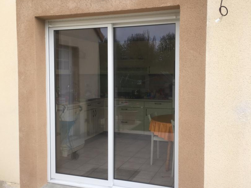 Baie vitrée coulissante PVC blanche sur terrasse donnant sur une cuisine
