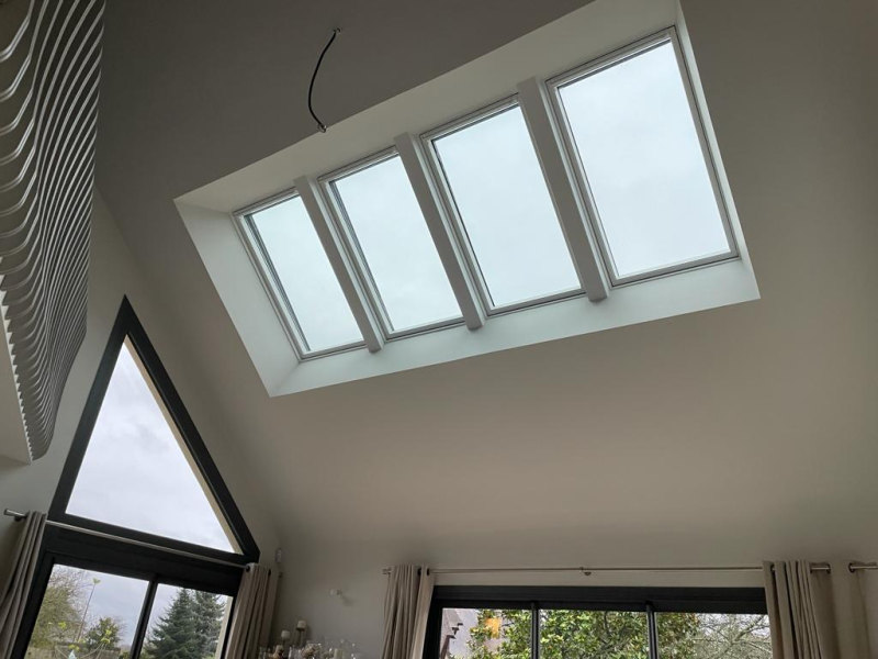 Quatre fenêtres de toit PVC blanches alignées sous plafond cathédrale