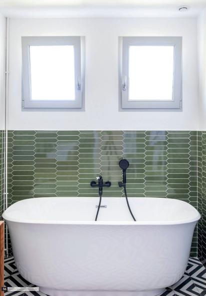 Deux fenêtres carrées à cadres gris au-dessus d'une baignoire blanche, carrelage vert