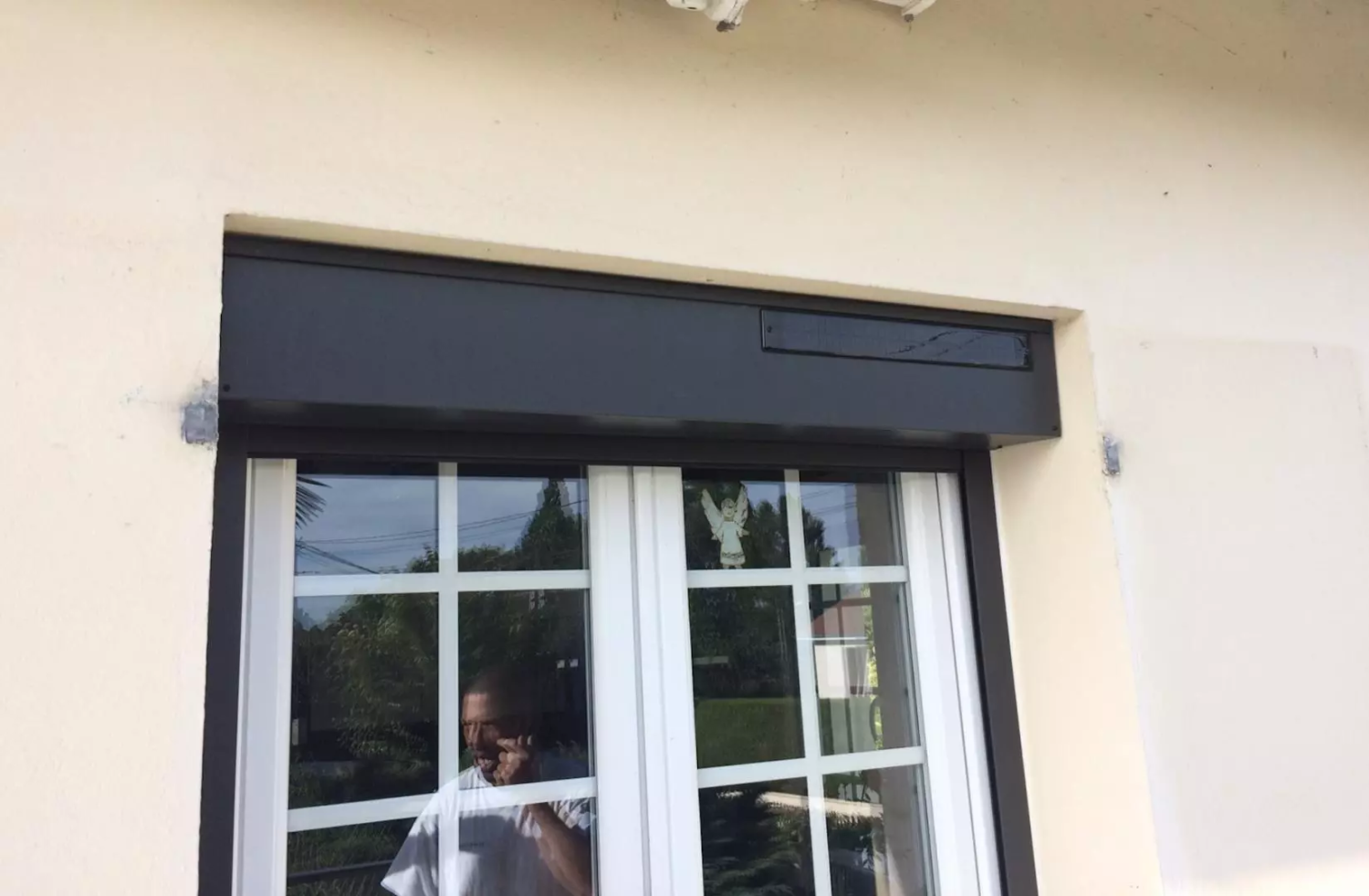 Volets roulants et brise-soleil gris sur façade blanche et grise d'immeuble