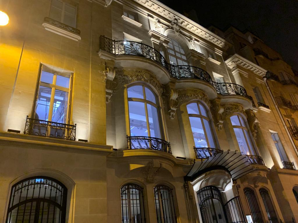 Fenêtres cintrées blanches à balcons en fer forgé sur façade en pierre, de nuit