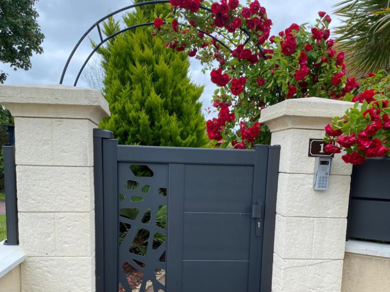 Portillon anthracite à panneau ajouré et lames pleines sous arche de roses rouges