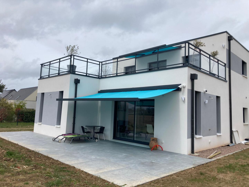 Store banne turquoise déployé sur terrasse carrelée d'une maison blanche et grise