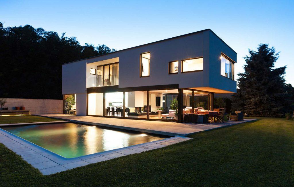Grande baie vitrée anthracite sur maison blanche moderne, piscine au crépuscule