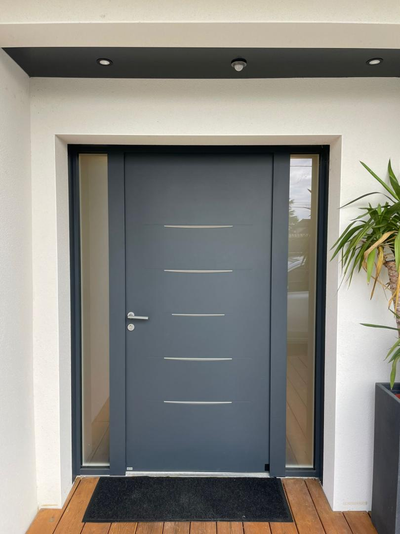 Porte d'entrée anthracite à inserts métalliques et vitrages latéraux, deck bois