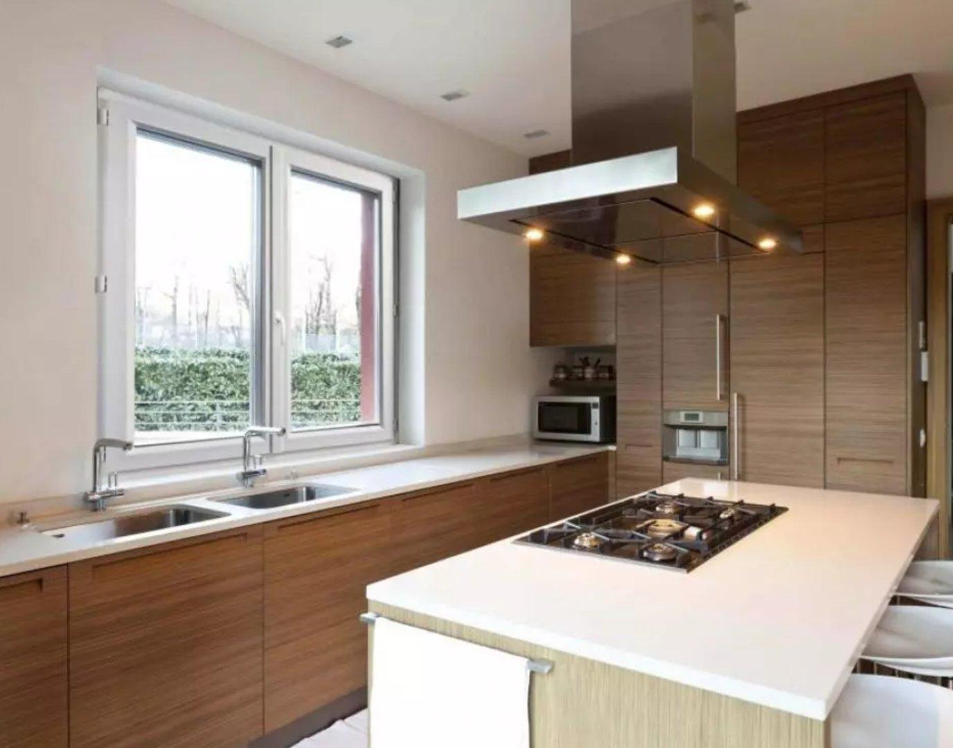 Fenêtre PVC blanche à deux vantaux au-dessus d'un évier de cuisine, vue sur haie