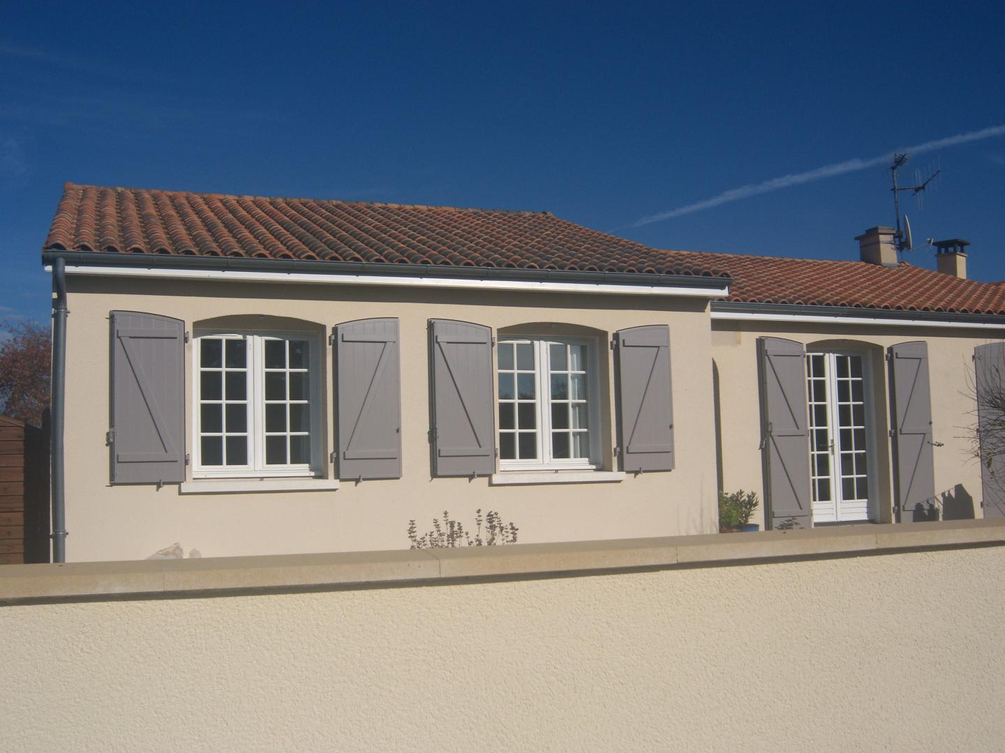 Volets battants gris et menuiseries blanches à petits bois sur maison crépi crème