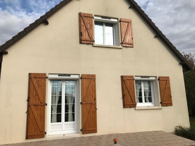 Menuiseries blanches à petits bois et volets bois marron, coffres solaires façade crème