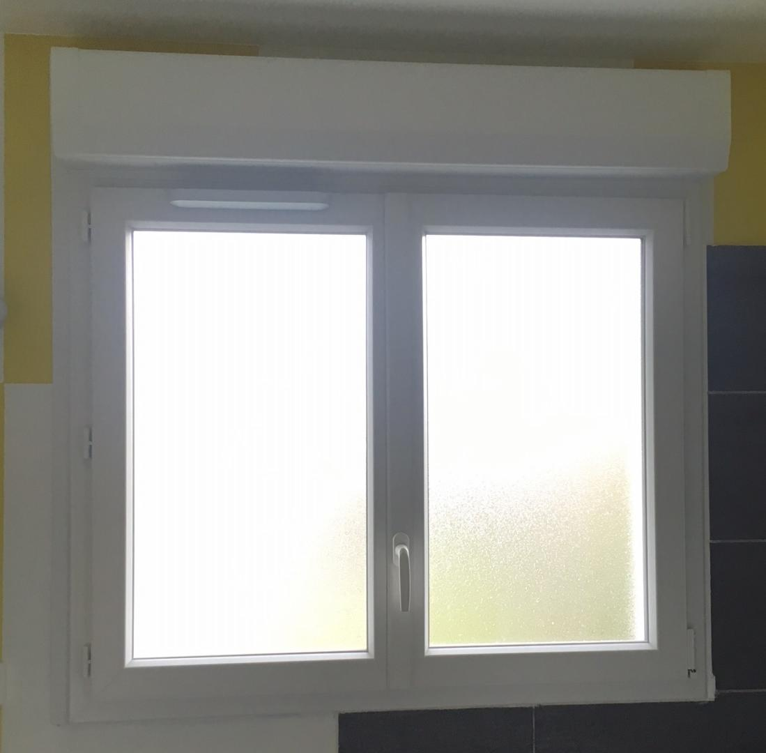 Fenêtre PVC blanche à vitrage dépoli et coffre de volet roulant, mur jaune